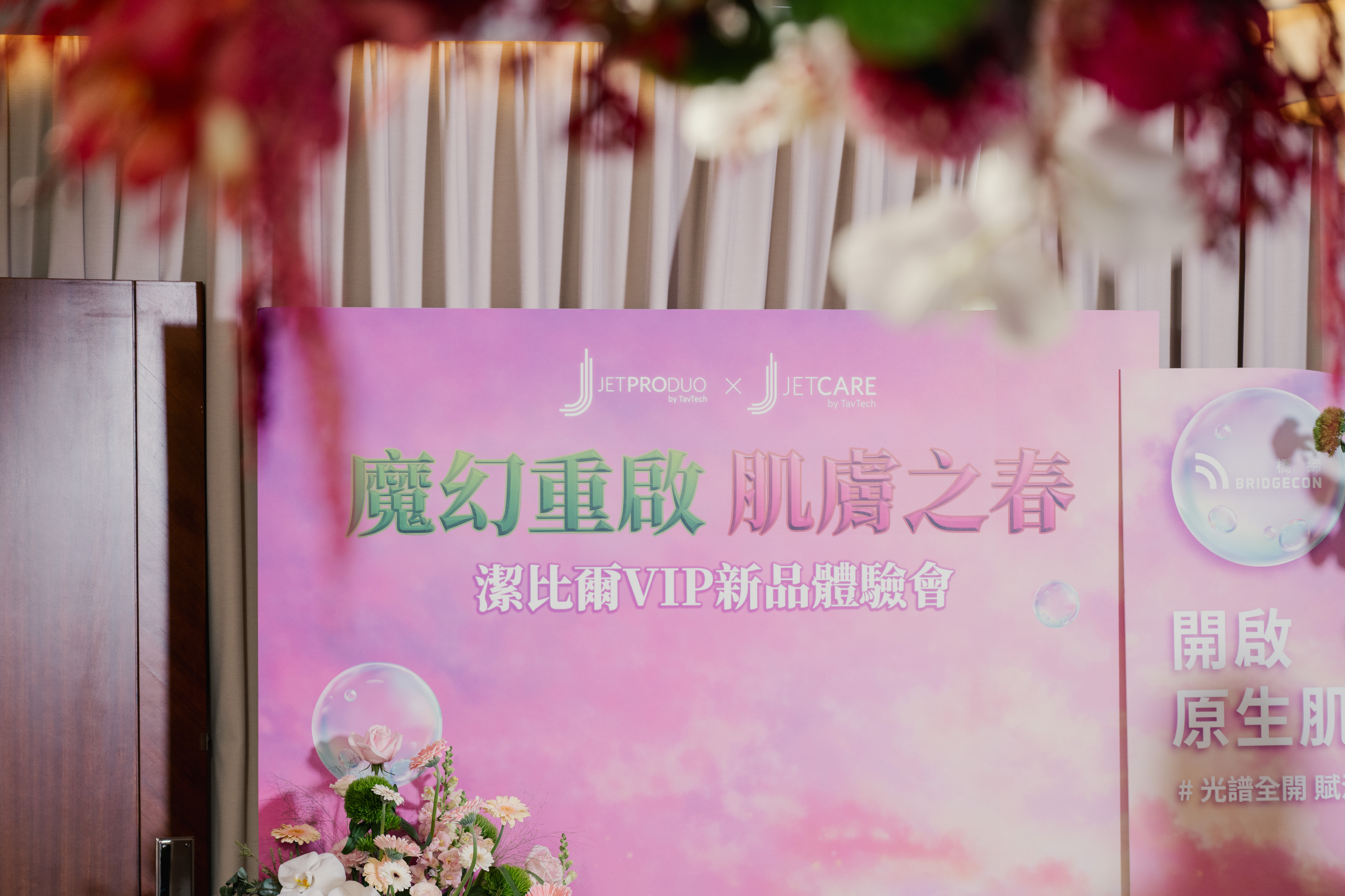 醫美品牌活動軟裝設計_潔比爾JETPEEL品牌主背板近景，精緻花藝裝飾與品牌識別設計