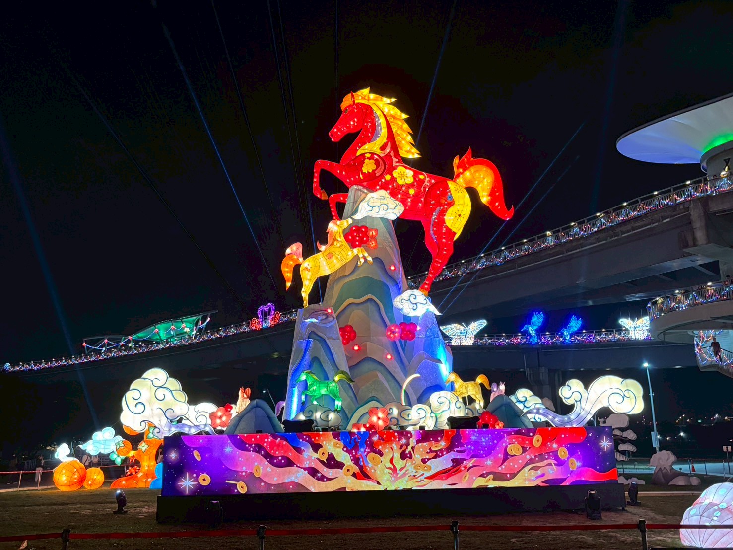 新北元宵燈會工程管理_大型駿馬主燈裝置夜間點燈效果，紅金色馬身搭配山形基座與LED波浪光帶